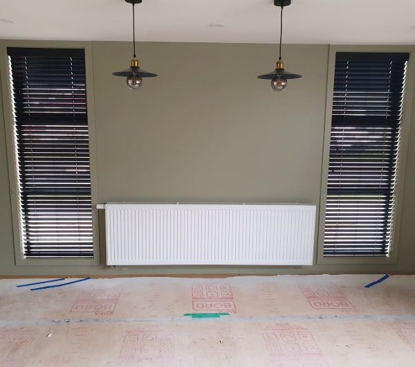 A panel radiator installed under a window in a finished Otago living room