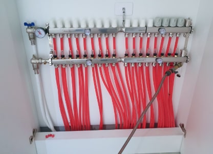 An underfloor heating manifold with the heating loops fanning out below it, in a Dunedin home