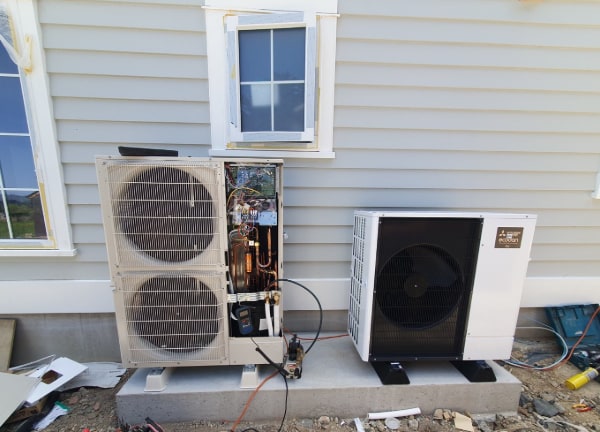 Two air-to-water heat pump outdoor units on a concrete plinth at an Otago new build