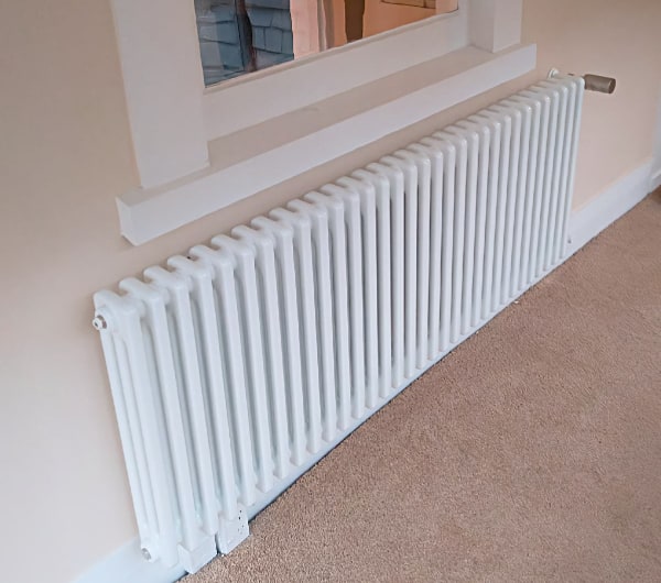 A white column radiator retrofitted under a window in an existing Otago home